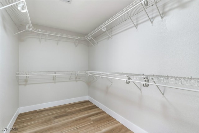 walk in closet with wood finished floors