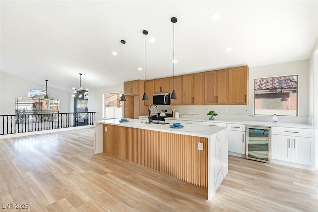 kitchen with wine cooler, stainless steel appliances, a sink, light wood-style floors, and light countertops