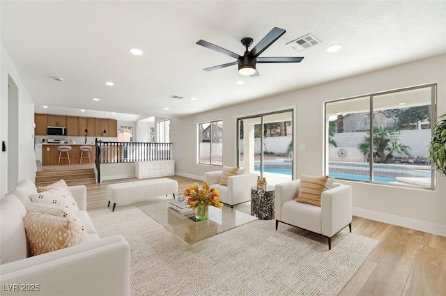 living area featuring light wood-style floors, visible vents, a wealth of natural light, and recessed lighting