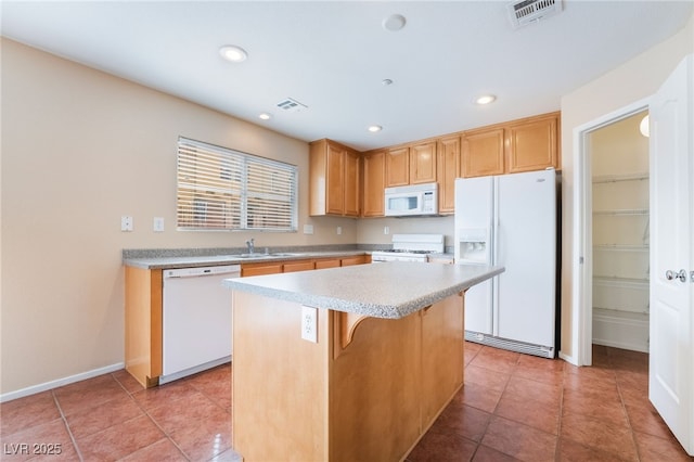 kitchen featuring white appliances, visible vents, a sink, and a center island