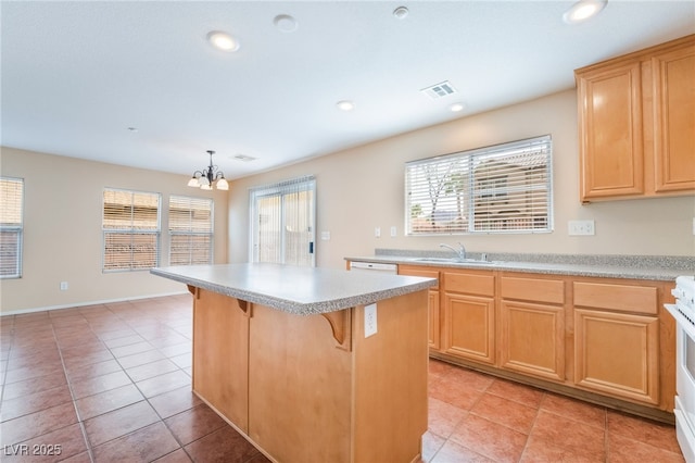 kitchen featuring a kitchen island, a sink, light countertops, light brown cabinetry, and a kitchen bar