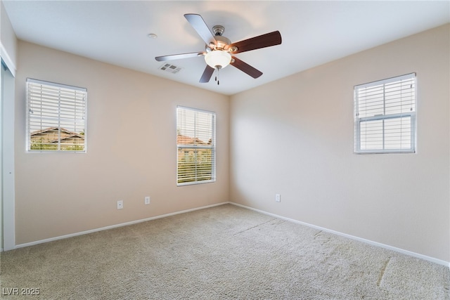 carpeted spare room with ceiling fan, visible vents, and baseboards