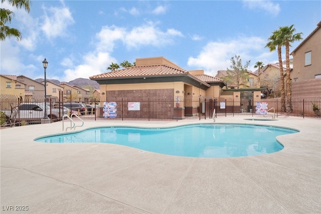 community pool with a patio area, fence, and a residential view