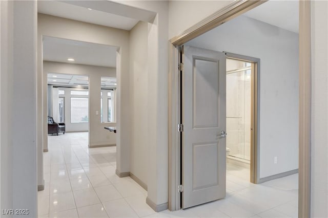 corridor with light tile patterned floors and baseboards