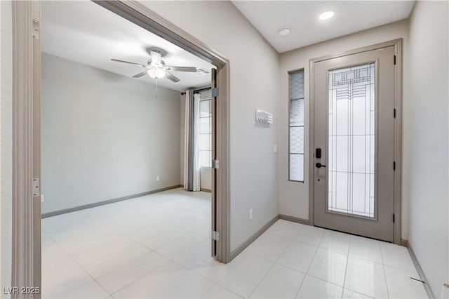 foyer entrance with ceiling fan and baseboards