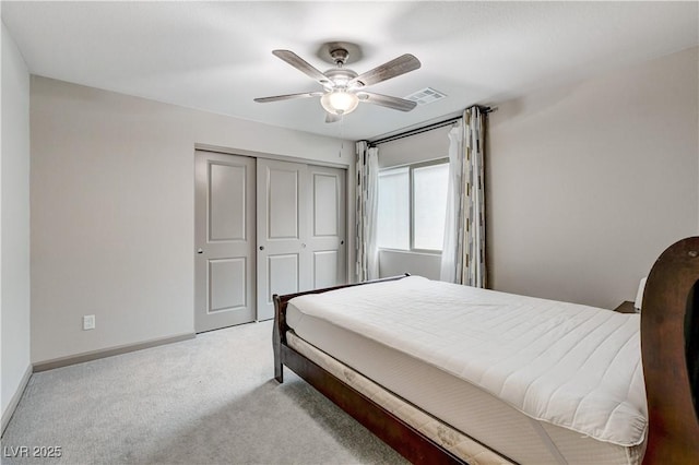 bedroom featuring ceiling fan, light colored carpet, visible vents, baseboards, and a closet