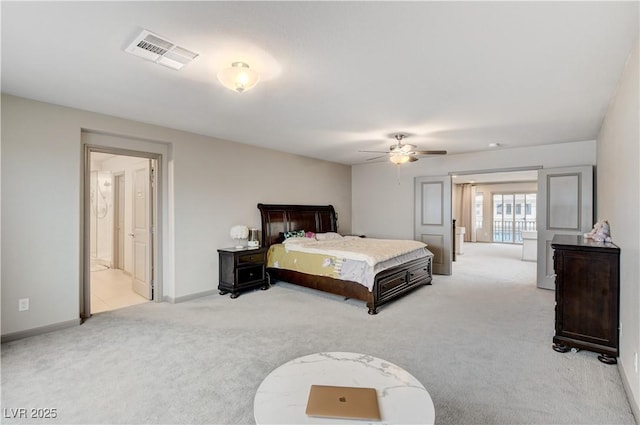 bedroom featuring visible vents, ensuite bathroom, a ceiling fan, light carpet, and baseboards