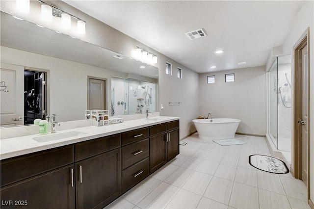 full bathroom featuring double vanity, a stall shower, visible vents, and a sink