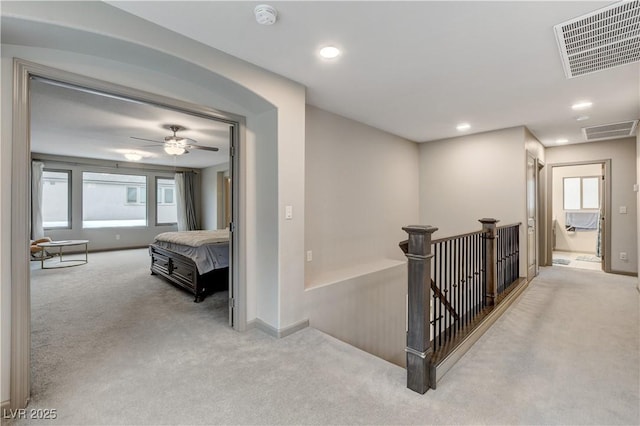 hall featuring carpet floors, visible vents, a wealth of natural light, and an upstairs landing