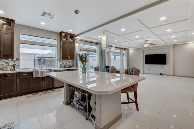 kitchen with tasteful backsplash, visible vents, a breakfast bar area, light countertops, and a sink