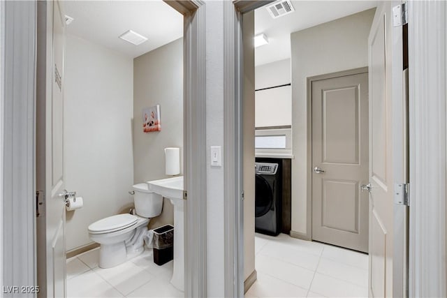 half bath with toilet, tile patterned flooring, visible vents, and washer / clothes dryer