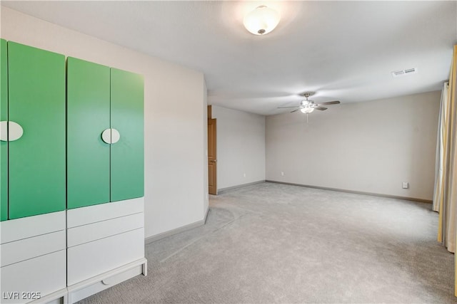 carpeted spare room with a ceiling fan, visible vents, and baseboards