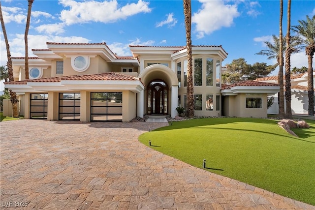 mediterranean / spanish-style house featuring decorative driveway, a tile roof, and stucco siding