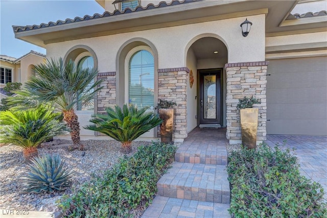 view of exterior entry featuring stone siding, an attached garage, and stucco siding