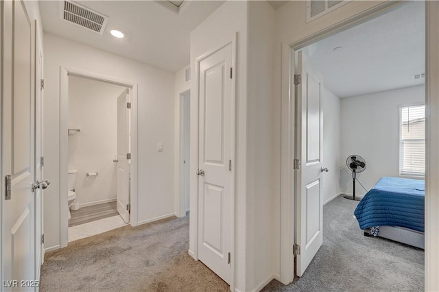 hallway featuring carpet, visible vents, and baseboards