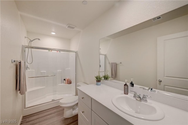 full bathroom featuring visible vents, a shower stall, toilet, and wood finished floors