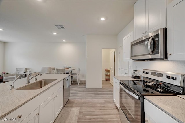 kitchen with visible vents, appliances with stainless steel finishes, light wood-style floors, open floor plan, and a sink