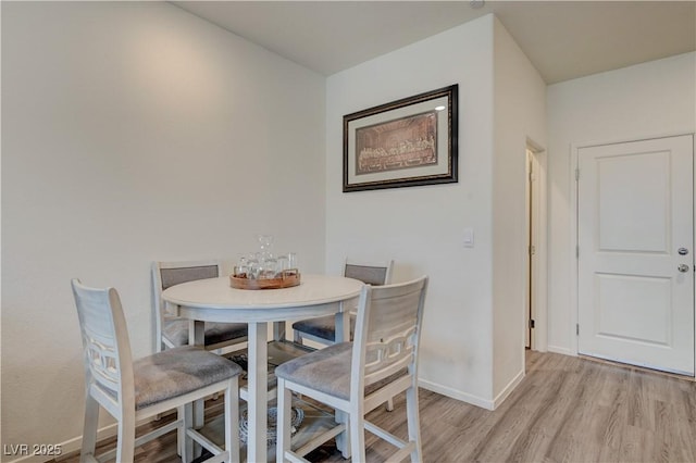 dining room featuring light wood finished floors and baseboards