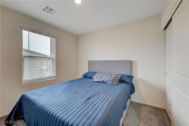 carpeted bedroom featuring baseboards, visible vents, and a closet