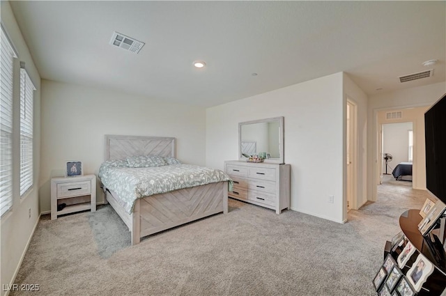 bedroom with visible vents, light carpet, and baseboards