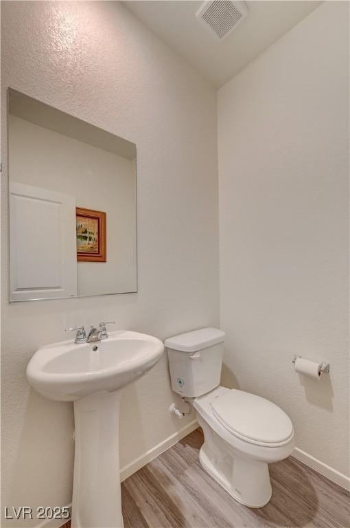 bathroom with toilet, baseboards, visible vents, and wood finished floors