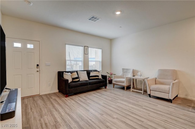 living room featuring light wood finished floors, baseboards, and visible vents