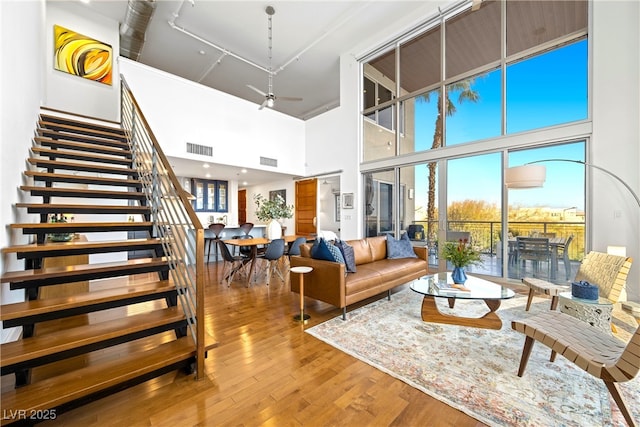 living room with a ceiling fan, stairs, visible vents, and wood finished floors