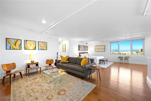 living area with rail lighting, wood-type flooring, and baseboards