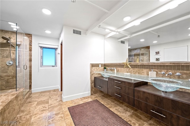 bathroom featuring visible vents, a sink, backsplash, and a shower stall