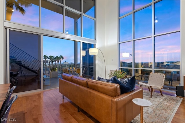 living room featuring expansive windows, wood finished floors, and a towering ceiling