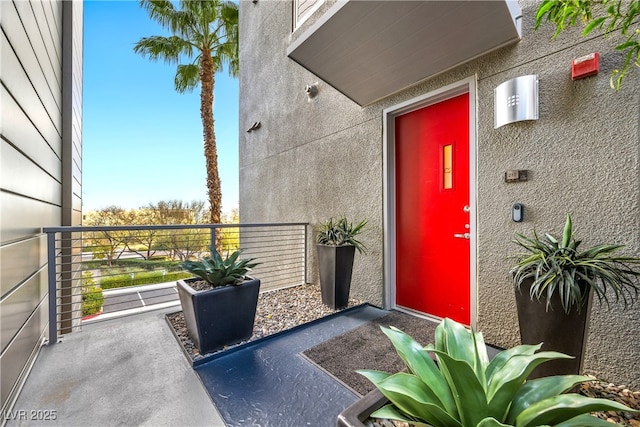 property entrance featuring a balcony and stucco siding