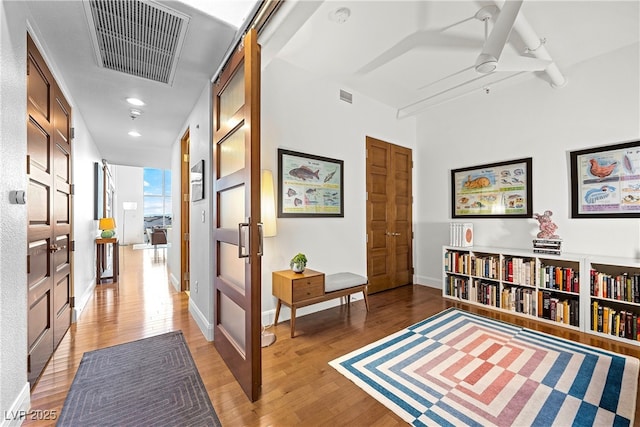 hallway with light wood-style floors, baseboards, and visible vents