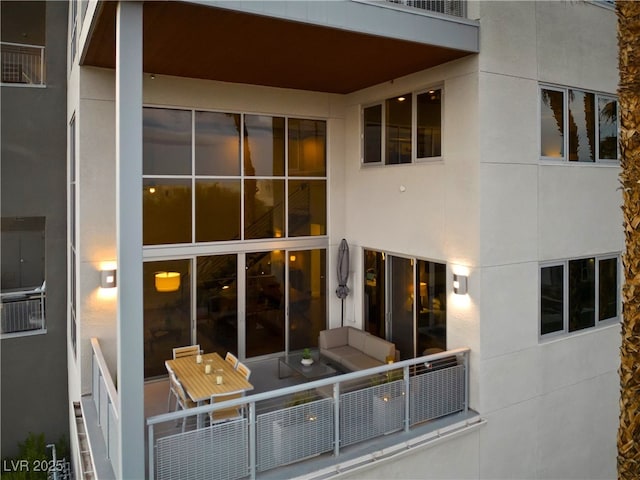 rear view of house featuring a balcony and stucco siding