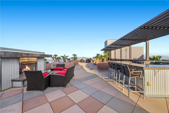 view of patio / terrace featuring outdoor dry bar and a multi sided fireplace