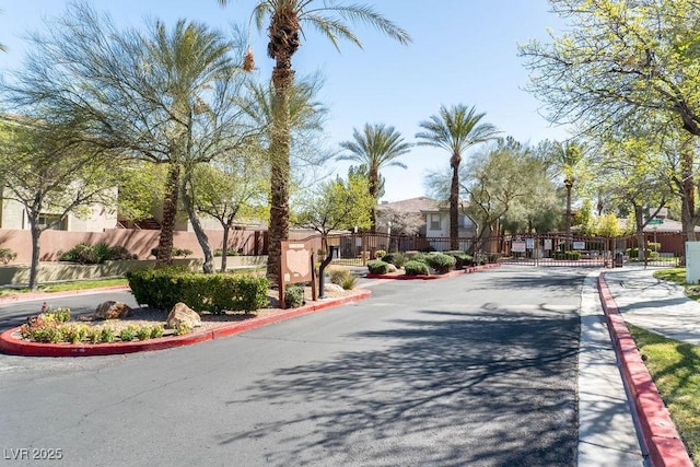 view of road with a gated entry, a gate, a residential view, and curbs