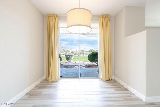 spare room with baseboards and wood finished floors