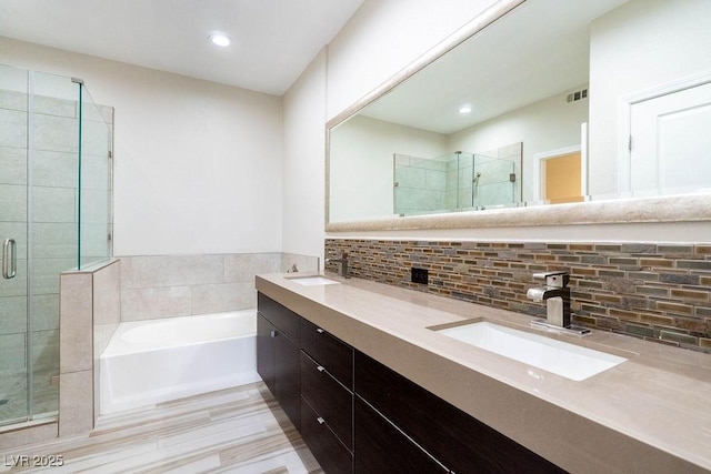 bathroom with backsplash, a garden tub, a sink, and a shower stall