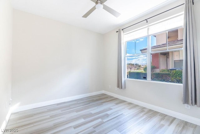 spare room with wood finished floors, a ceiling fan, and baseboards