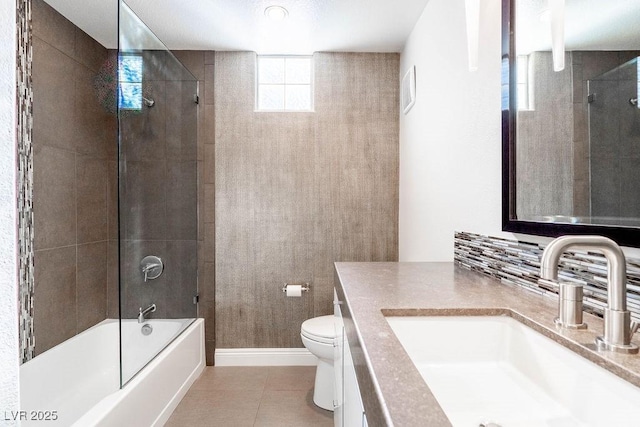 bathroom featuring tile patterned floors, toilet, baseboards, bathtub / shower combination, and vanity