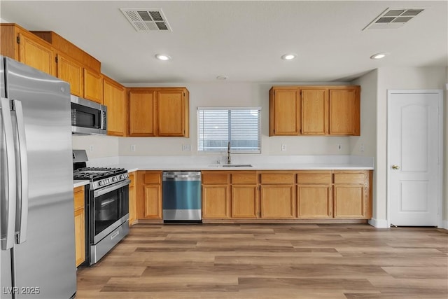kitchen with light countertops, appliances with stainless steel finishes, a sink, and visible vents