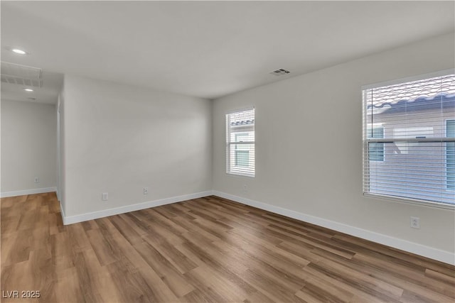 empty room with baseboards, recessed lighting, wood finished floors, and visible vents