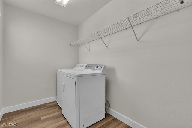 laundry area with baseboards, laundry area, light wood finished floors, and washing machine and clothes dryer