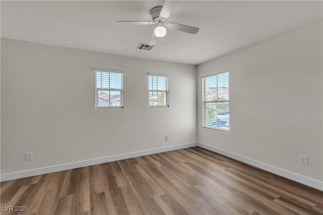 unfurnished room with baseboards, plenty of natural light, wood finished floors, and visible vents