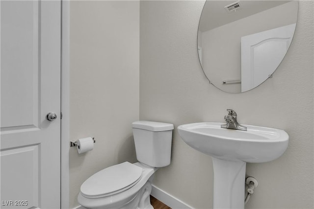bathroom featuring baseboards, toilet, and visible vents