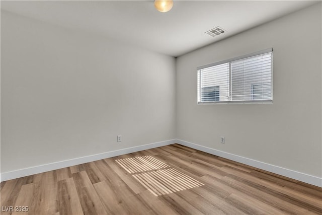 empty room featuring light wood-style floors, baseboards, and visible vents