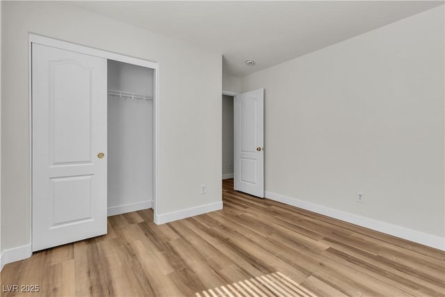 unfurnished bedroom with baseboards, light wood-style flooring, and a closet