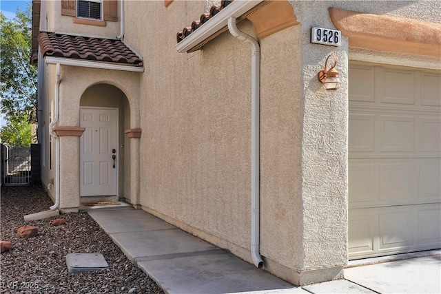 view of exterior entry featuring stucco siding and a tiled roof