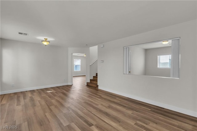 unfurnished living room featuring visible vents, a healthy amount of sunlight, and wood finished floors