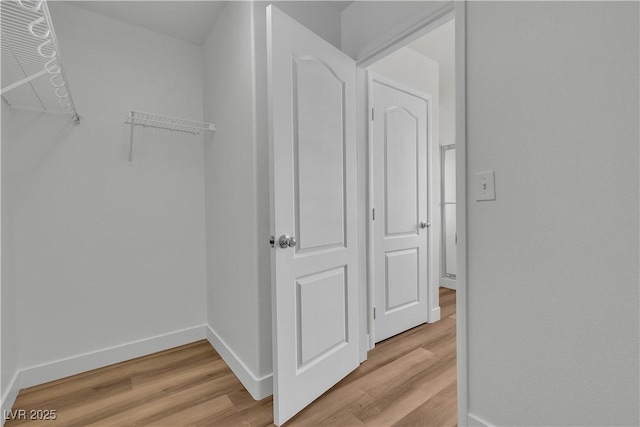 walk in closet with light wood finished floors