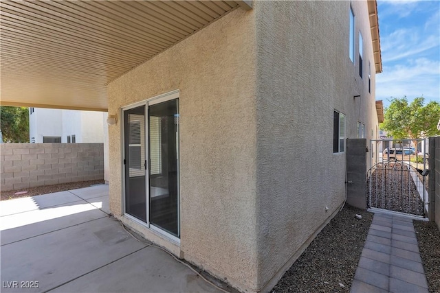 view of home's exterior with a patio, fence, a gate, and stucco siding